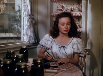 Movie still from “State Fair” (1945), directed by Walter Lang – A woman sitting at a table with a plate in front of her; Medium shot, Over the shoulder angle