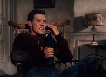 Movie still from “State Fair” (1945), directed by Walter Lang – A man sitting in a rocking chair talking on the phone; Medium shot, High angle
