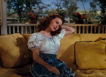 Movie still from “State Fair” (1945), directed by Walter Lang – A woman sitting on top of a yellow couch; Medium shot, High angle