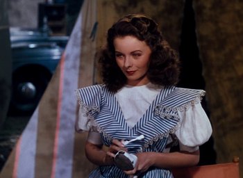 Movie still from “State Fair” (1945), directed by Walter Lang – A woman in a striped dress holding a camera; Medium shot, Over the shoulder angle