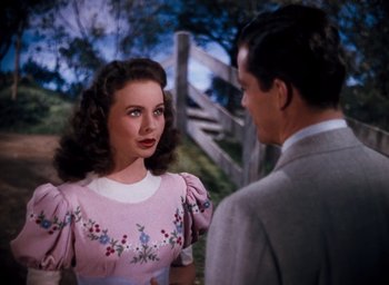 Movie still from “State Fair” (1945), directed by Walter Lang – A woman in a pink dress talking to a man in a gray suit; Medium shot, Over the shoulder angle