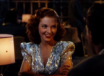 Movie still from “State Fair” (1945), directed by Walter Lang – A woman in a sequined dress smiling for the camera; Close Up shot, Over the shoulder angle