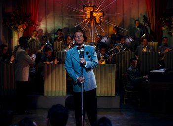 Movie still from “State Fair” (1945), directed by Walter Lang – A man holding a microphone while standing in front of an audience; Wide shot, High angle