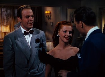 Movie still from “State Fair” (1945), directed by Walter Lang – A man and a woman talking to a man in a suit and bow tie; Medium shot, Over the shoulder angle