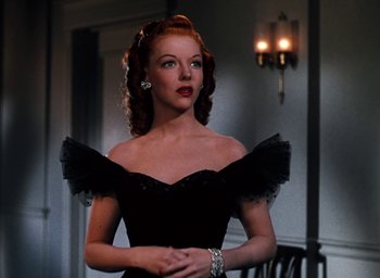 Movie still from “State Fair” (1945), directed by Walter Lang – A woman in a black dress standing next to a wall; Medium shot, Over the shoulder angle