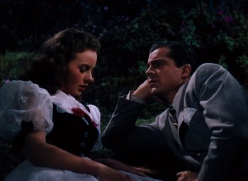 Movie still from “State Fair” (1945), directed by Walter Lang – A man and a woman sitting next to each other on the ground; Medium shot, High angle