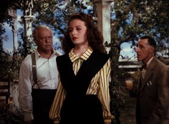 Movie still from “State Fair” (1945), directed by Walter Lang – A woman standing next to two men on a porch; Medium shot, Low angle