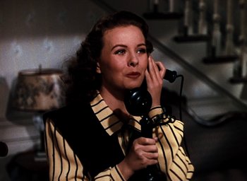 Movie still from “State Fair” (1945), directed by Walter Lang – A woman talking on a black and white phone while wearing a yellow striped shirt; Close Up shot, High angle