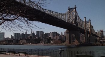 Movie still from “State of Grace” (1990), directed by Phil Joanou – A man standing next to a body of water near a bridge; Extreme Wide shot, High angle