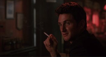 Movie still from “State of Grace” (1990), directed by Phil Joanou – A man is smoking a cigarette in a dark room; Close Up shot, Low angle