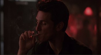 Movie still from “State of Grace” (1990), directed by Phil Joanou – A man smoking a cigarette in a dark room; Close Up shot, Low angle