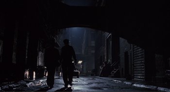 Movie still from “State of Grace” (1990), directed by Phil Joanou – Two people walking down a dark street at night; Wide shot, High angle