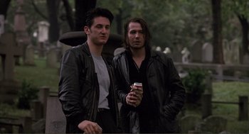 Movie still from “State of Grace” (1990), directed by Phil Joanou – A couple of men standing next to each other holding drinks; Medium shot, Low angle