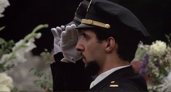 Movie still from “State of Grace” (1990), directed by Phil Joanou – A man wearing a hat and a white glove is saluting; Close Up shot, Low angle