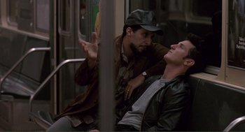 Movie still from “State of Grace” (1990), directed by Phil Joanou – Two men on a subway train one of which is lying on the ground; Medium shot, Over the shoulder angle