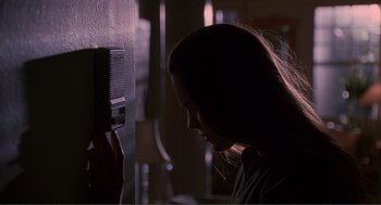 Movie still from “State of Grace” (1990), directed by Phil Joanou – A woman is looking at a radio in a dark room; Close Up shot, Low angle
