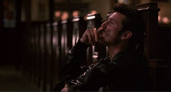 Movie still from “State of Grace” (1990), directed by Phil Joanou – A man in a leather jacket is smoking a cigarette; Close Up shot, Low angle
