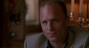 Movie still from “State of Grace” (1990), directed by Phil Joanou – A person wearing a suit and tie; Close Up shot, Over the shoulder angle