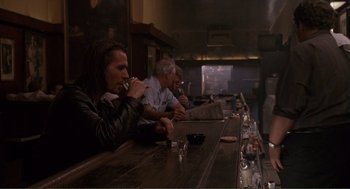 Movie still from “State of Grace” (1990), directed by Phil Joanou – A group of people sitting at a bar drinking; Medium shot, Over the shoulder angle