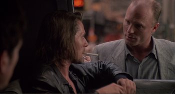 Movie still from “State of Grace” (1990), directed by Phil Joanou – A man sitting next to another man smoking a cigarette; Close Up shot, Over the shoulder angle