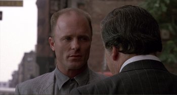 Movie still from “State of Grace” (1990), directed by Phil Joanou – A man wearing a suit and tie talking to another man wearing a suit and tie; Close Up shot, Over the shoulder angle