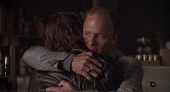 Movie still from “State of Grace” (1990), directed by Phil Joanou – A man and a woman hugging each other in a dark room; Close Up shot, Over the shoulder angle