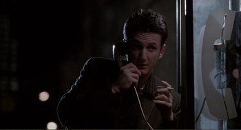 Movie still from “State of Grace” (1990), directed by Phil Joanou – A man is holding a phone and smoking a cigarette; Close Up shot, Low angle