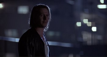 Movie still from “State of Grace” (1990), directed by Phil Joanou – A man with long hair standing in the dark at night; Close Up shot, Over the shoulder angle