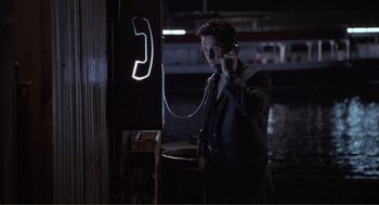 Movie still from “State of Grace” (1990), directed by Phil Joanou – A man talking on a phone next to a phone booth; Medium shot, High angle