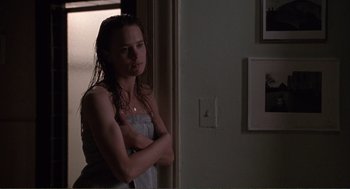 Movie still from “State of Grace” (1990), directed by Phil Joanou – A woman standing next to a wall with her arms crossed; Medium shot, Over the shoulder angle