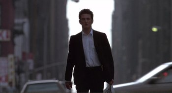Movie still from “State of Grace” (1990), directed by Phil Joanou – A man wearing a suit and tie walking down a street; Medium shot, Low angle