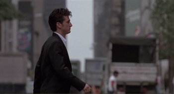 Movie still from “State of Grace” (1990), directed by Phil Joanou – A man in a suit is riding a bicycle; Medium shot, Low angle