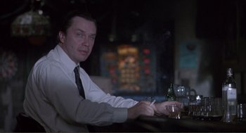 Movie still from “State of Grace” (1990), directed by Phil Joanou – A man sitting at a bar with a cigarette in his hand; Medium shot, Low angle