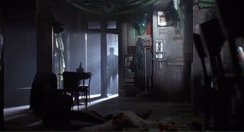 Movie still from “State of Grace” (1990), directed by Phil Joanou – A man standing in a room next to an open door; Wide shot, Low angle
