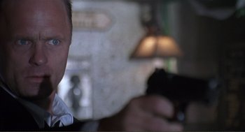 Movie still from “State of Grace” (1990), directed by Phil Joanou – A man is holding a gun in his hand; Close Up shot, Low angle