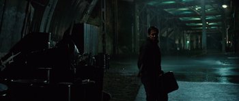 Movie still from “State of Play” (2009), directed by Kevin Macdonald – A man standing in the dark holding a bag; Wide shot, Low angle