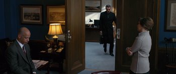 Movie still from “State of Play” (2009), directed by Kevin Macdonald – A man in a suit and tie walking through a door way; Wide shot, High angle