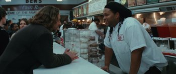 Movie still from “State of Play” (2009), directed by Kevin Macdonald – A man standing at a counter talking to another man in front of a counter; Medium shot, Over the shoulder angle