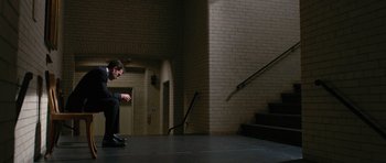 Movie still from “State of Play” (2009), directed by Kevin Macdonald – A man sitting on the ground in front of a staircase; Wide shot, Low angle