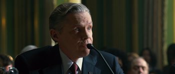 Movie still from “State of Play” (2009), directed by Kevin Macdonald – A person speaking on a microphone; Close Up shot, Over the shoulder angle