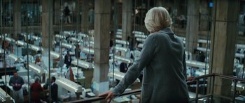 Movie still from “State of Play” (2009), directed by Kevin Macdonald – A woman standing on a rail in a room filled with benches; Medium shot, Low angle