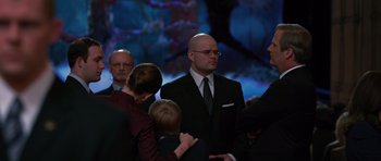 Movie still from “State of Play” (2009), directed by Kevin Macdonald – A group of people standing around each other wearing suits and ties; Medium shot, Over the shoulder angle