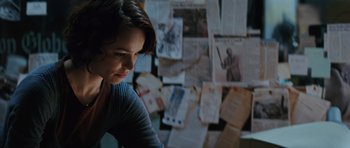 Movie still from “State of Play” (2009), directed by Kevin Macdonald – A woman sitting in front of a wall covered with papers; Close Up shot, Over the shoulder angle