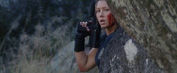 Movie still from “Stealth” (2005), directed by Rob Cohen – A woman holding a gun while standing next to a tree; Close Up shot, Low angle