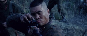 Movie still from “Stealth” (2005), directed by Rob Cohen – A man holding a camera while standing next to a tree; Close Up shot, Over the shoulder angle