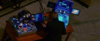 Movie still from “Stealth” (2005), directed by Rob Cohen – A man sitting in front of a laptop computer on top of a table; Medium shot, High angle