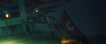 Movie still from “Stealth” (2005), directed by Rob Cohen – A man with a gun and a flag in the dark; Wide shot, Low angle