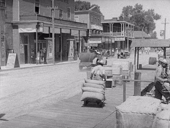 Movie still from “Steamboat Bill, Jr.” (1928), directed by Buster Keaton – An old photo of a street in a town; Extreme Wide shot, High angle