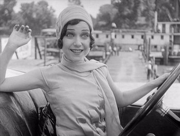 Movie still from “Steamboat Bill, Jr.” (1928), directed by Buster Keaton – An old photo of a woman sitting in the driver's seat of an old car; Medium shot, High angle