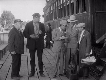 Movie still from “Steamboat Bill, Jr.” (1928), directed by Buster Keaton – A black and white photo of a group of men standing next to each other; Medium shot, Low angle